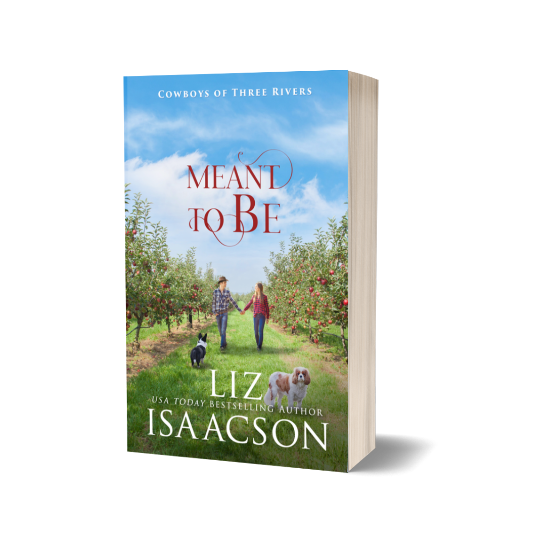 Paperback of 'Meant to Be' by Liz Isaacson with a couple and dogs in an apple orchard.