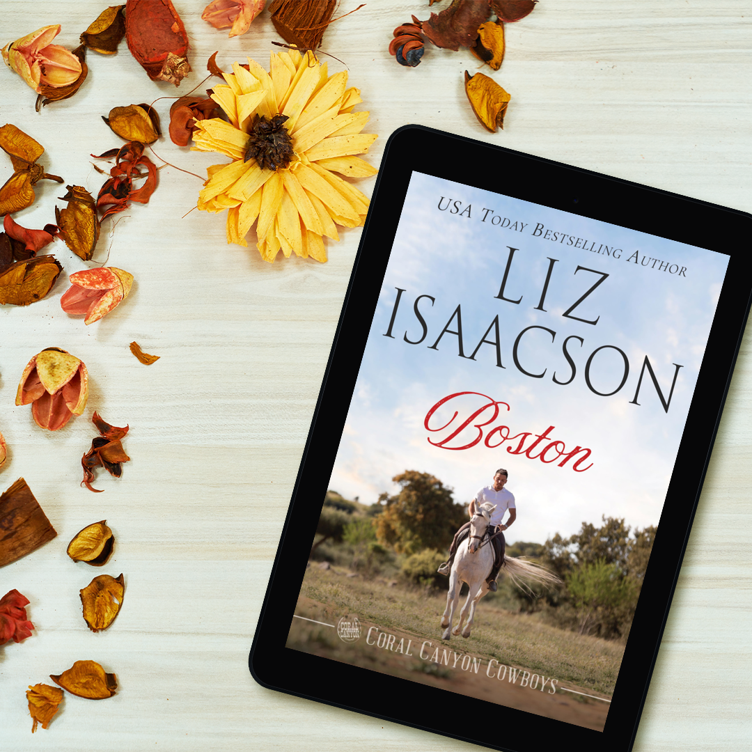 Tablet displaying the cover of Boston by Liz Isaacson on a white table with fall leaves and flowers.