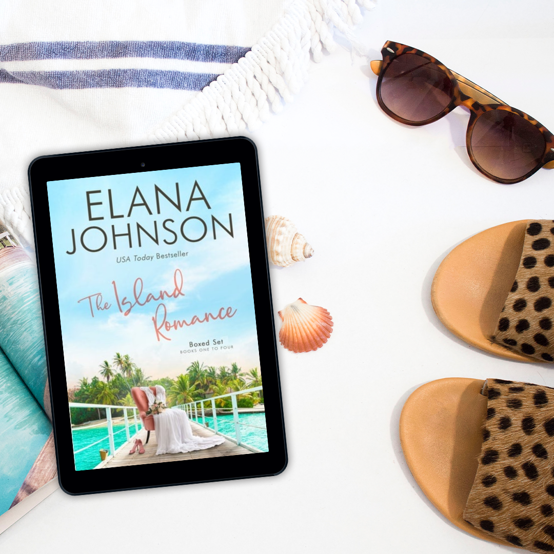 Tablet displaying 'The Island Romance' by Elana Johnson with sunglasses and a hat on a white surface