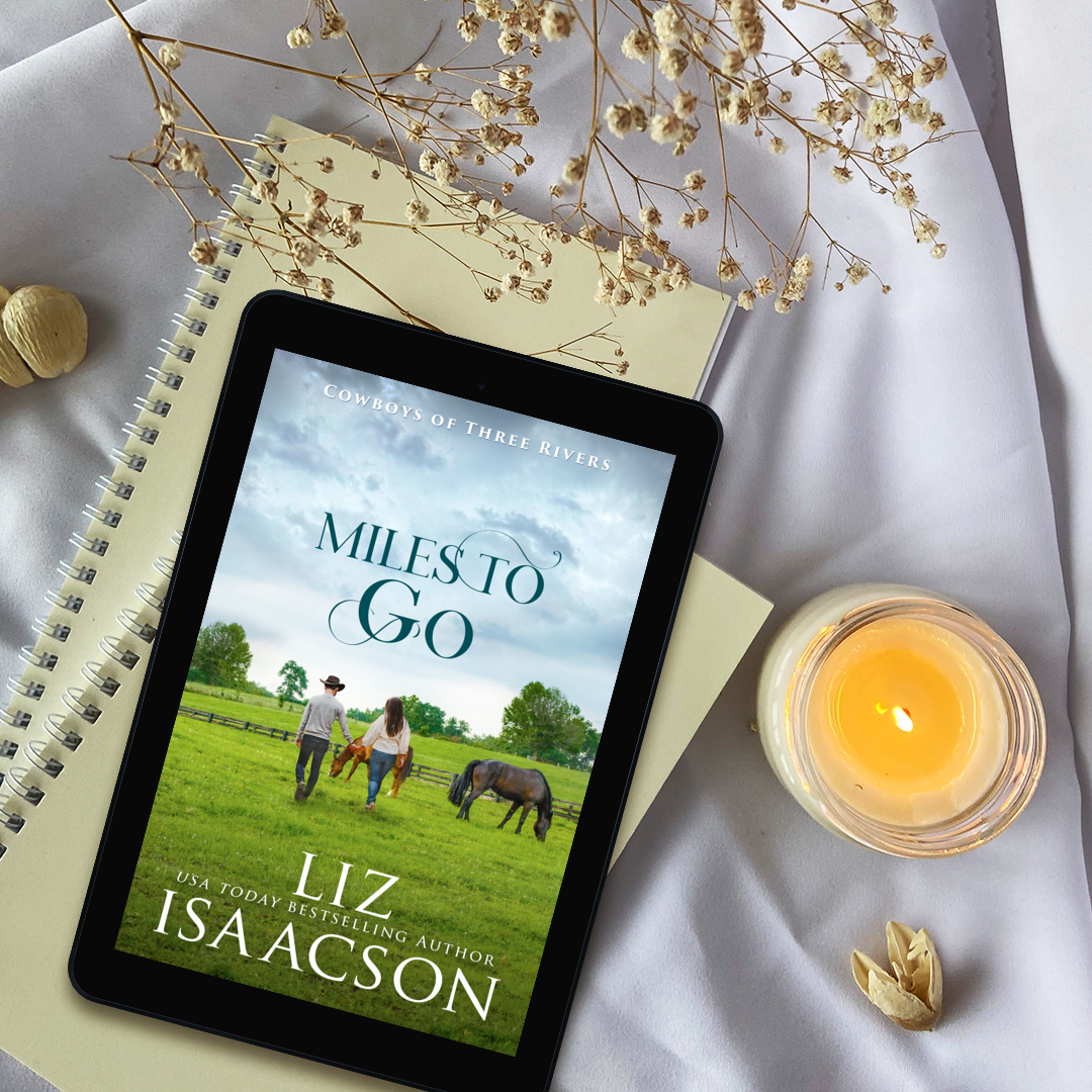 E-reader displaying 'Miles to Go' by Liz Isaacson with a candle and dried flowers on a white surface