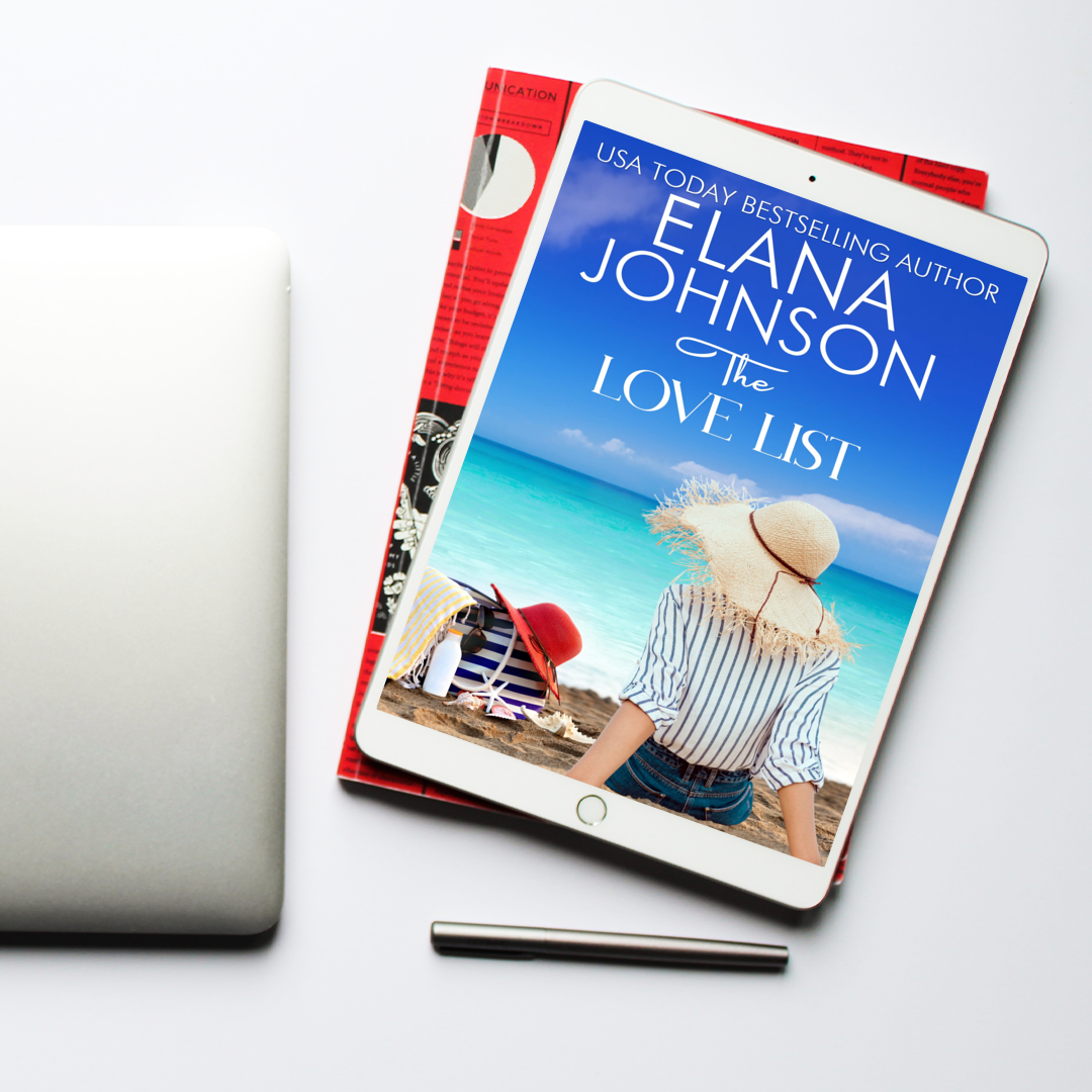 Tablet displaying the ebook The Love List by Elana Johnson, placed on top of magazines beside a closed laptop and a pen on a clean white surface.
