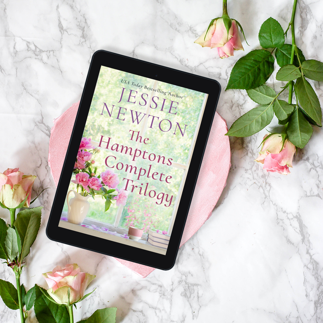 E-reader displaying 'The Hamptons Complete Trilogy' by Jessie Newton on a marble surface with pink roses.