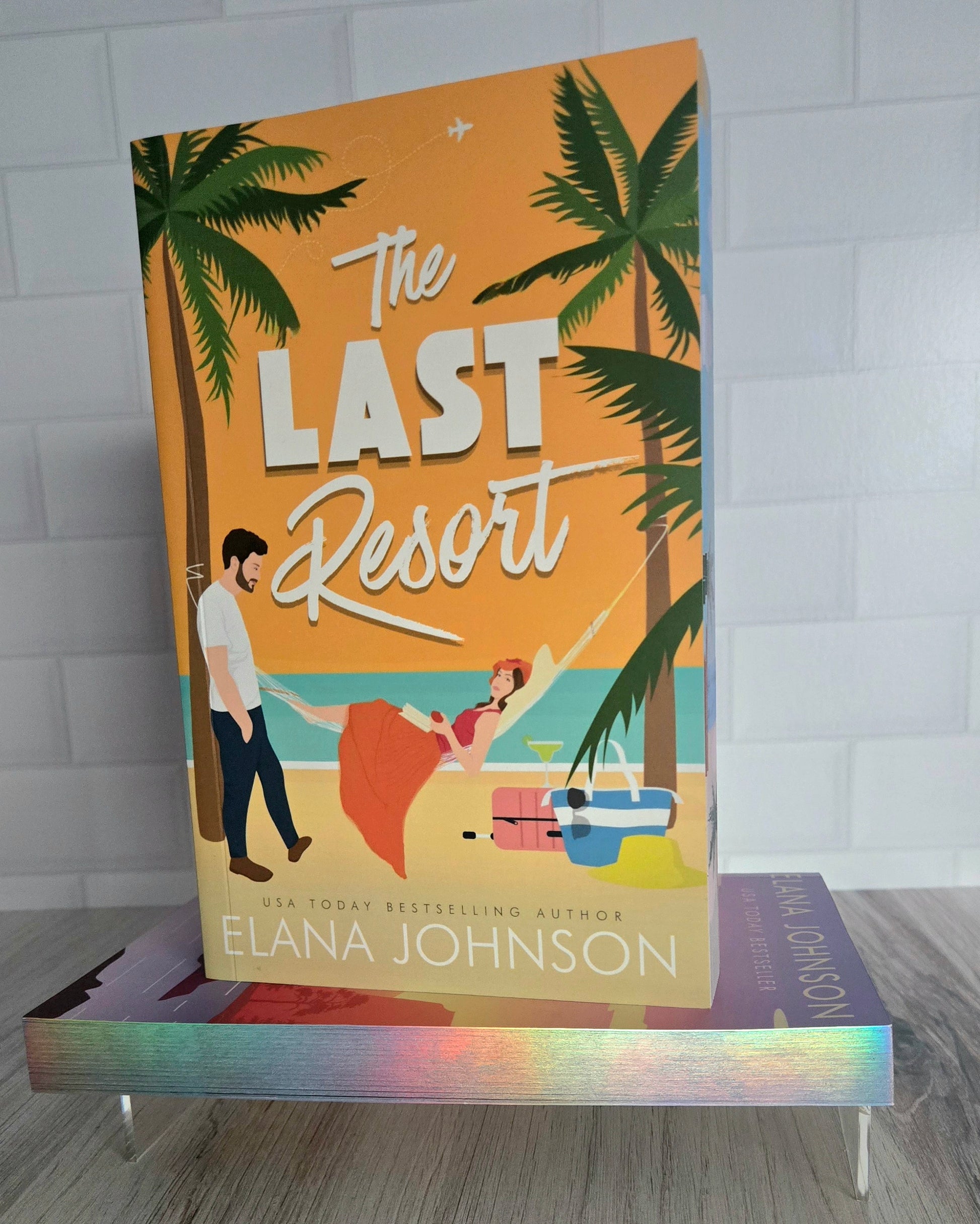 Book titled 'The Last Resort' by Elana Johnson with a beach scene cover on a stand.
