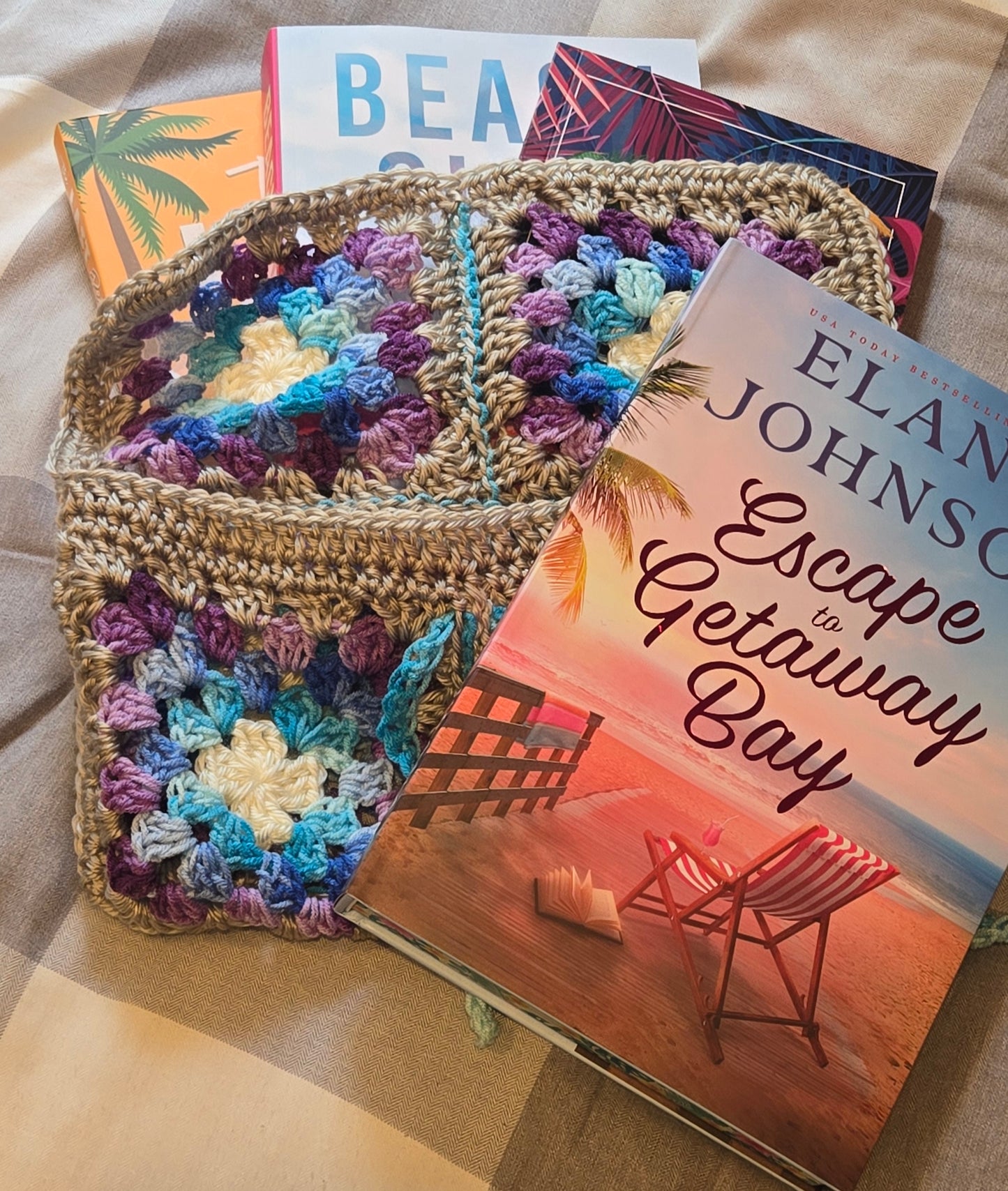 Colorful crocheted bag next to a book titled 'Escape to Getaway Bay' by Elan Johnson.