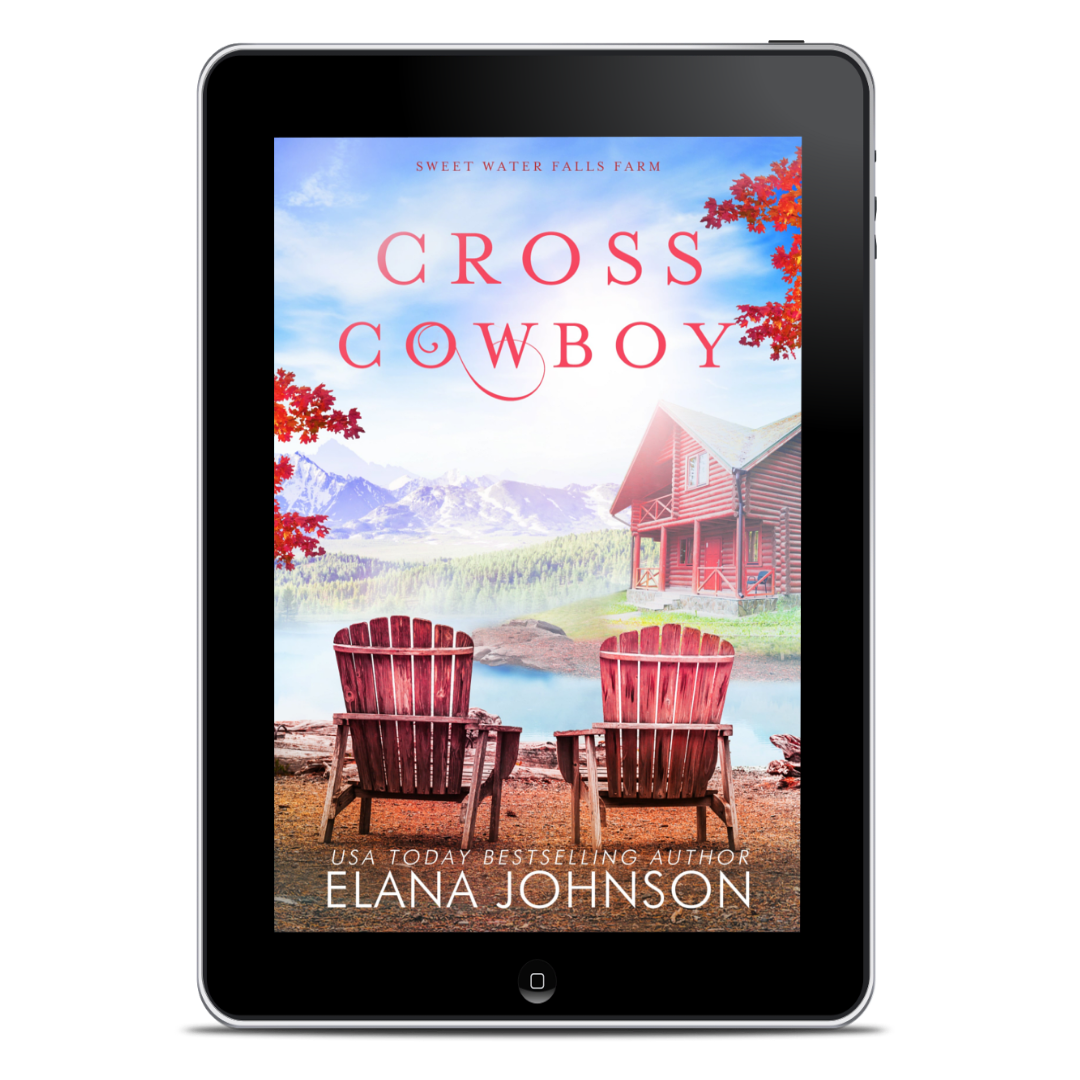 A tablet device displaying the book cover for 'Cross Cowboy' by Elana Johnson. The cover art shows a lakeside cabin, two red Adirondack chairs, red mountains, and red autumn leaves, with the title in large red letters and the author name at the bottom.