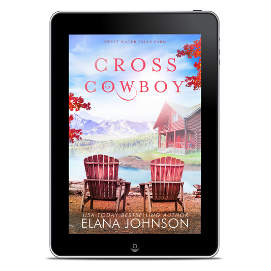 A tablet device displaying the book cover for 'Cross Cowboy' by Elana Johnson. The cover art shows a lakeside cabin, two red Adirondack chairs, red mountains, and red autumn leaves, with the title in large red letters and the author name at the bottom.